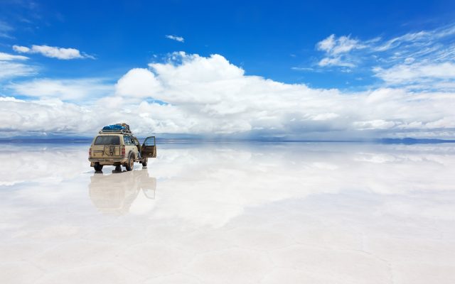 Jeep on the reflected surface of Salar de Uyuni lake in Bolivia